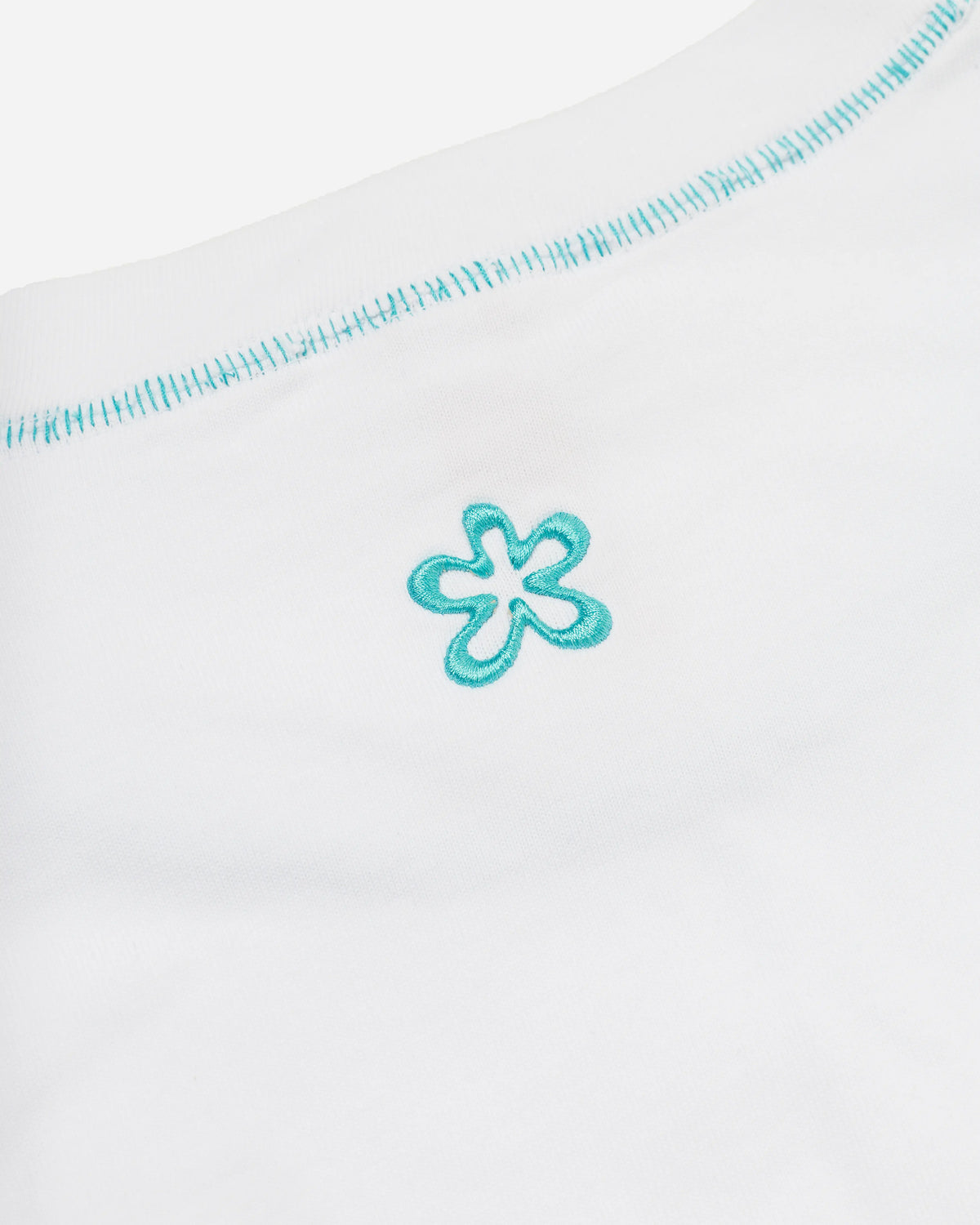 Close-up white cotton t-shirt, featuring a small blue embroidered ERIK-YVON flower motif and blue contrast stitching along the crew neck.