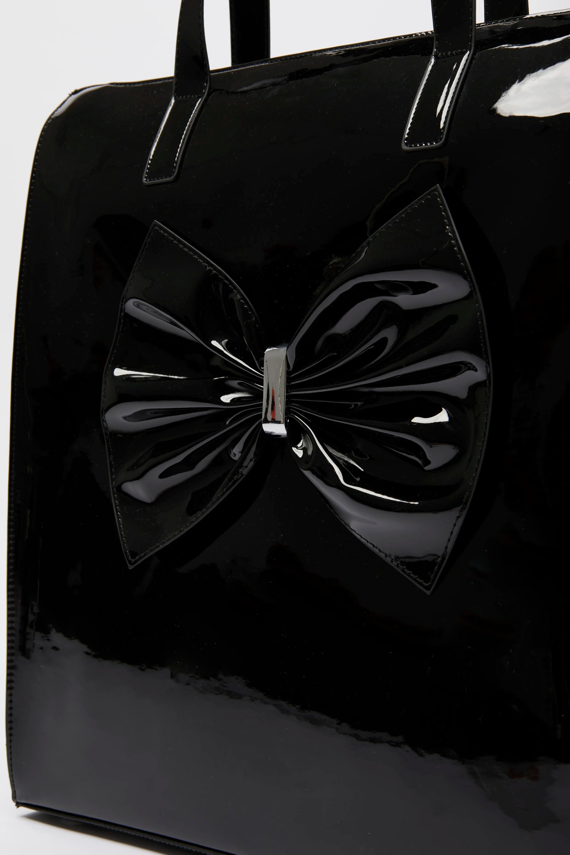 Black patent leather handbag with a large bow detail.