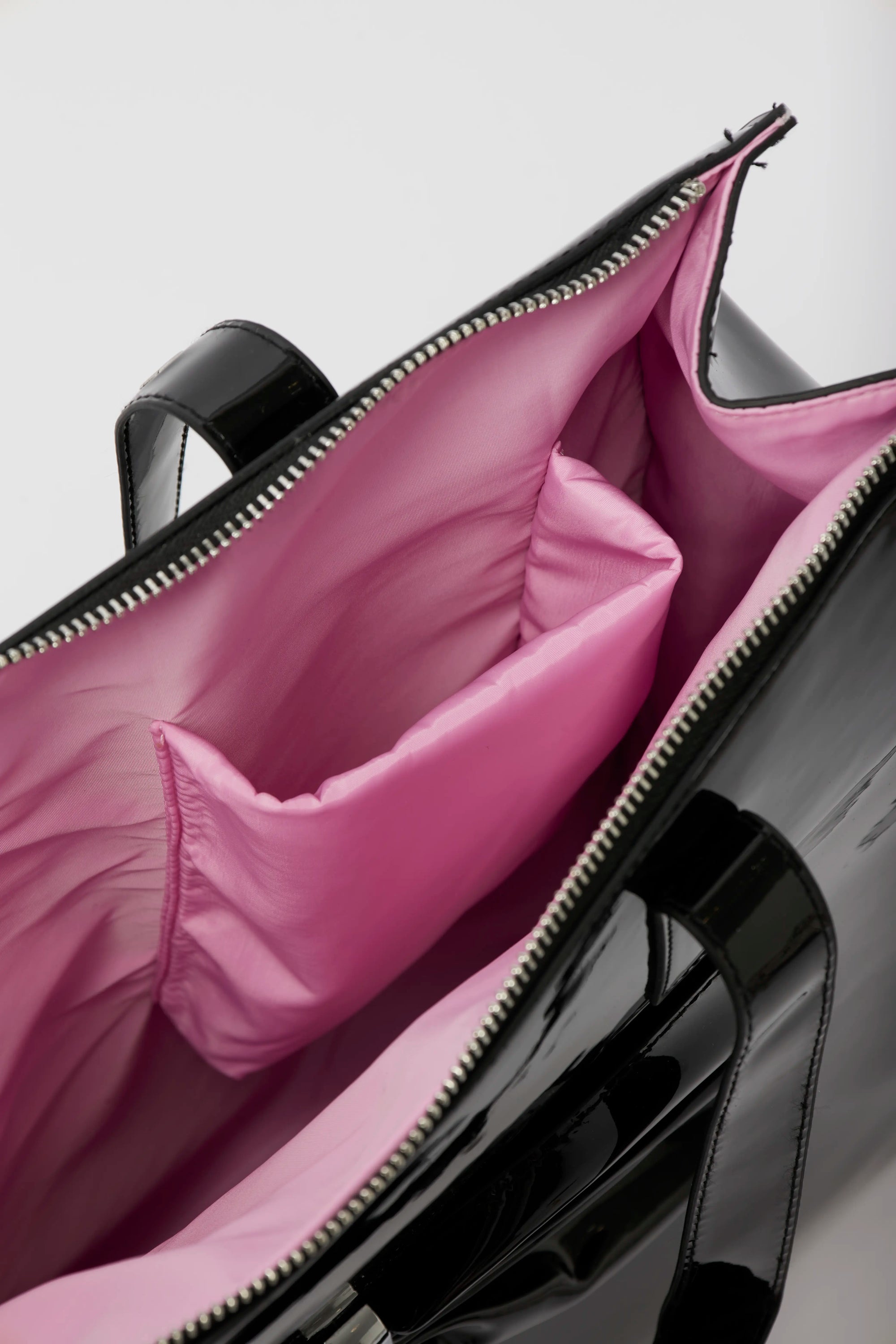 Black suitcase with pink interior pocket open, showing pink lining.