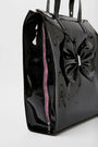 Oversized patent tote bag in black with a bow embellishment on the side, zipper closure, and a glossy finish.
