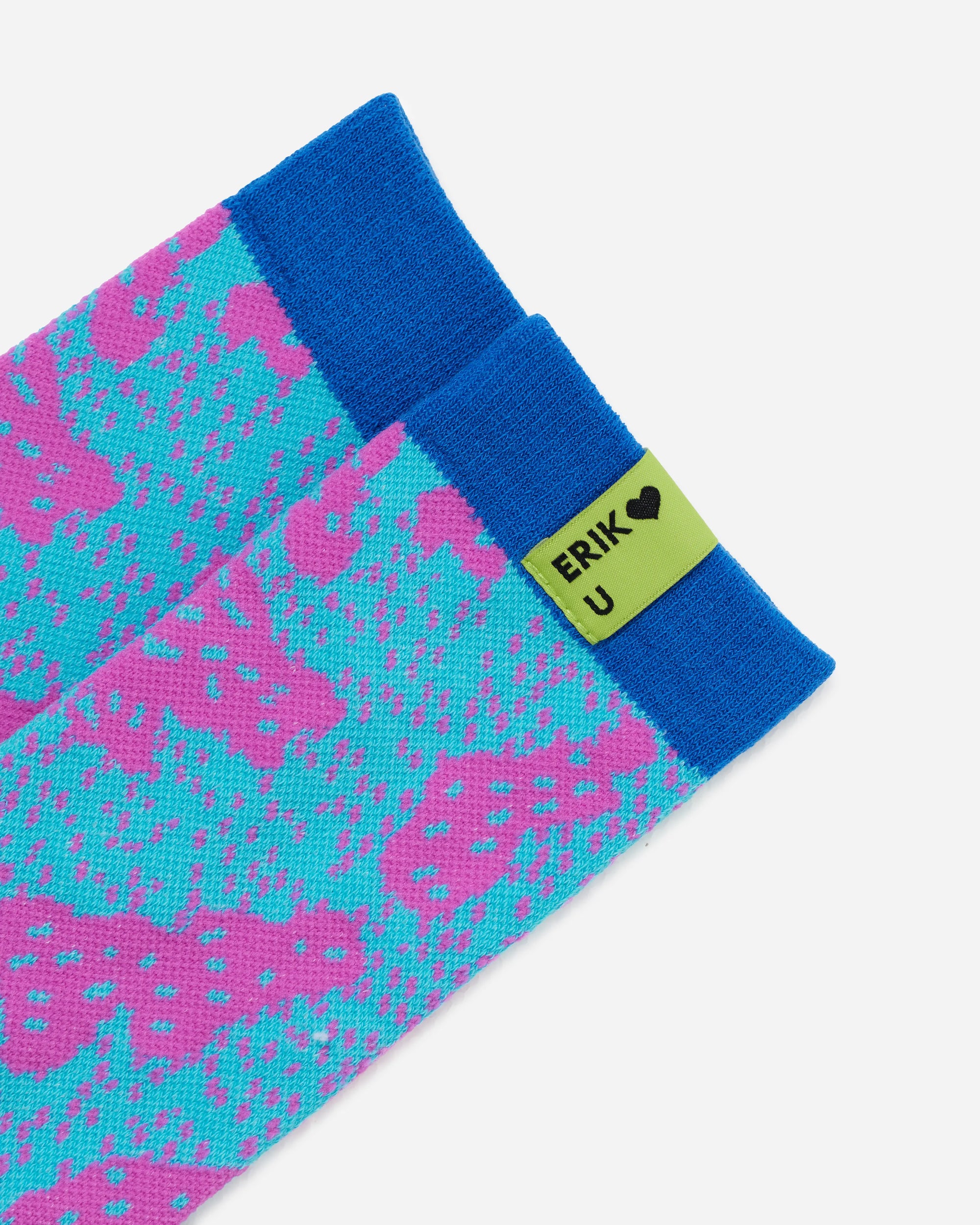 A close-up of a pair of patterned socks with a bright blue cuff and a lime green tag that reads 'ERIK <3 U' with a small heart. The sock body features a repeating pattern of pink and turquoise shapes on a light blue base.